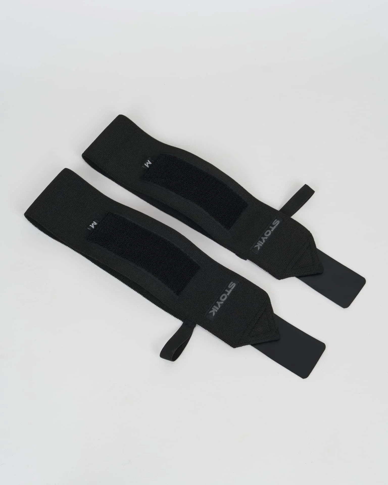 Paire de bandes de poignets de musculation STOYIK noires taille M vue à plat sur fond blanc