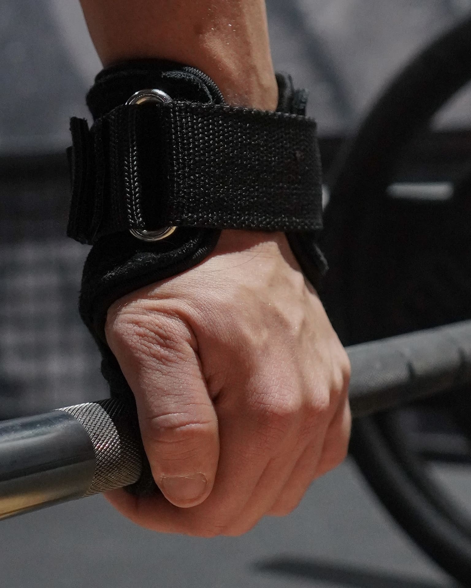 Main serrant une barre d'haltérophilie, soutenue par une sangle de tirage STOYIK Athletics pour maximiser l'efficacité de l'entraînement
