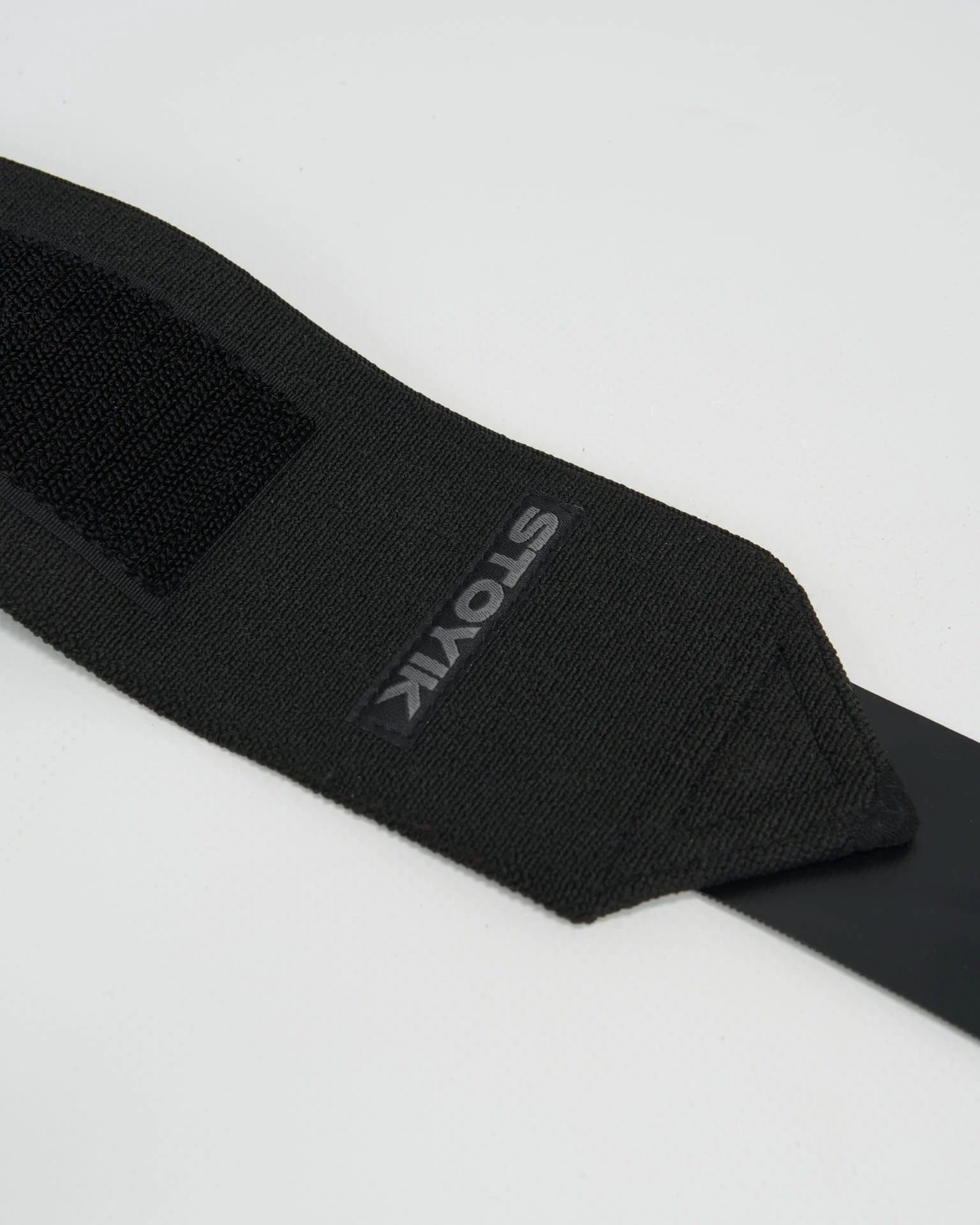 Zoom sur la bande de poignet de musculation STOYIK noire avec logo visible et fermeture velcro