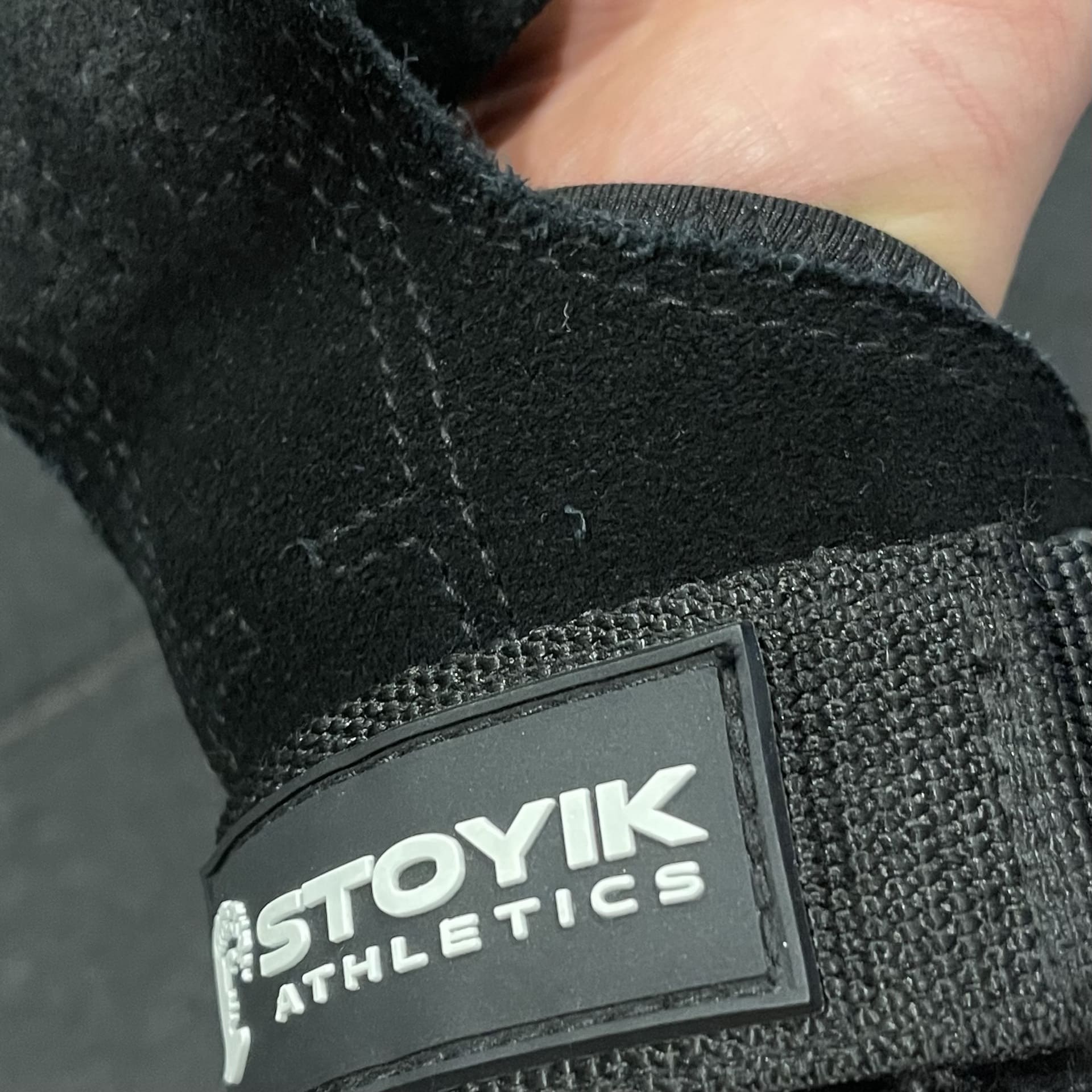 Gros plan sur une sangle de tirage STOYIK Athletics en cuir velours, mettant en évidence la qualité de la couture et le logo de la marque